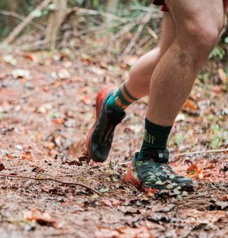 A close up view of the feet of two runners running on a trail.